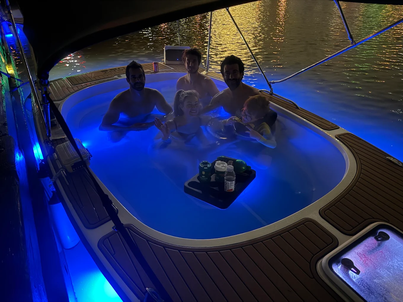 Guests enjoying the blue LED-lit hot tub boat during a real night cruise